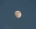 Scenery of an airplane in the blue sky crossing over the image of the Moon Royalty Free Stock Photo