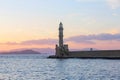 Scenery with beautiful ancient lighthouse surrounded by the sea. Sunset sky with pink light. High mountains. Greece, Chania.