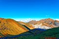 Scenery of colorful autumn mountains under blue clear sunny sky with a hiking trail in the valley & volcanic gas