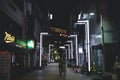 Scenery of a couple walking through a modern alley with bright light during night time in Busan Royalty Free Stock Photo