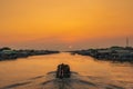 The scenery of the fishing community where a fishing boat is sailing in the canal to go out to sea to find fish in the evening