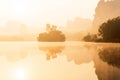 Scenery landscape of tropical lake in the morning mist, golden sun shining down on the lake and mountain range backdrop Royalty Free Stock Photo