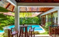 Scenery of luxury villa among palm trees. Swimming pool with garden at tropical hotel