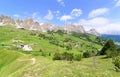 Scenery of majestic Gardena Pass on a sunny summer day with highways & hiking trails winding thru a green grassy Alpine valley