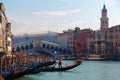 Scenery of romantic Venice before sunset, with view of a gondolier steering his ferry gondola by a pier, the famous landmark