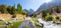 Scenery summer panorama of mountains, stormy mountain river and narrow track. Forest is along stormy mountain river