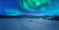 Scenic aerial night skies panorama on frozen lake, mountains with snow mobile traces, northern green lights. Scandinavian night Royalty Free Stock Photo