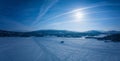 Scenic aerial panorama on frozen lake, mountains with snow mobile traces, sunny blue sky with plane traces, contrails. Royalty Free Stock Photo