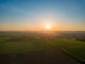 Scenic aerial view at beautiful spring sunset in a green shiny field with green grass and golden sun rays, deep blue Royalty Free Stock Photo