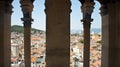 Scenic aerial view of the city through stone window from the bell tower, roofs of houses in old town, beautiful cityscape, sunny