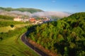 Scenic aerial view of the foggy Carpathian mountains, village and blue sky with clouds in morning light, summer rural landscape Royalty Free Stock Photo