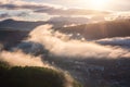 Scenic aerial view of the foggy Carpathian mountains, village and blue sky with clouds in morning light, summer rural landscape Royalty Free Stock Photo