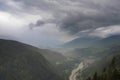 Scenic aerial view on villages in Dolomites with mountains in clouds on background and meadows on foreground Royalty Free Stock Photo