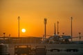 Scenic airplane silhouette parked to air stairs airport trucks air traffic control in front of sun at sunrise