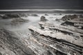 Scenic atlantic coastline with waves in motion around rocks on sandy beach in long exposure, bidart, basque country, france