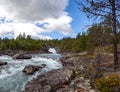 Scenic background with raging mountain river flows through stone rapids among the deserted rocks and forests of northern Norway. Royalty Free Stock Photo