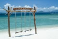 Scenic beach backdrop featuring a vivid blue ocean, with a wooden swing overlooking the horizon