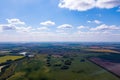 Scenic bird`s-eye view of farmland in the countryside, blue sky with white clouds, fields with green grass and trees, lakes and Royalty Free Stock Photo