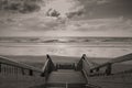 Scenic biscarrosse beach in sunset with clouds and wooden footpath stairs in black and white sepia, france Royalty Free Stock Photo