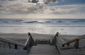 Scenic biscarrosse beach in sunset with clouds and wooden footpath stairs, france