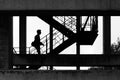 Scenic black and white shot of a silhouette of a man walking up on the staircase outdoors