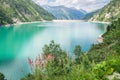 Turquoise or emerald colored reservoir lake in the Alps Royalty Free Stock Photo