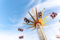 Scenic bottom view high chain swing flying carousel against blue sky. Merry go round roundabout chairoplane at portable