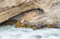 Boulder river rushing through a sea grotto and jagged rock wall in Montana