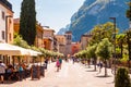 Scenic cityscape of Riva del Garda. Cozy city street full of tourists, plants and Italian architecture with high dolomite