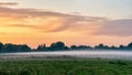 Scenic country landscape with fog over a meadow with trees in the early morning. End of summer, beginning of autumn Royalty Free Stock Photo