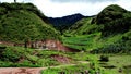 Scenic dirt road winding its way around a lush green mountainous landscape. Royalty Free Stock Photo