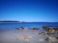 Scenic display of calm sea waves hitting the shoreline with big stones and smooth sand