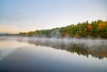 Scenic Early morning fog just above the water level of Connecticut River with colorful fall foliage reflected in calm water at