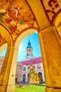 The scenic frescoes of the covered gallery of Loreta of Prague and its bell tower through the arcades, Czechia