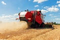 Scenic front view Big red powerful industrial combine harvester machine reaping golden ripe wheat cereal field on bright