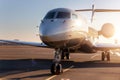 Scenic front view modern luxury expensive private jet plane parked airport taxiway hangar warm colorful dramatic evening Royalty Free Stock Photo