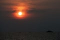 Scenic golden red sunset, Sun partly behind clouds, Tropical sky, silhouettes of military ship and small fishing boats at horizon Royalty Free Stock Photo