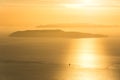 Scenic golden sunset over the ocean with lonely sailing boat and island in the background Royalty Free Stock Photo