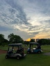 Scenic Golf Carts at Sunset on a Beautiful Golf Course with Dramatic Cloud Sky Royalty Free Stock Photo