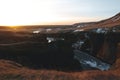 scenic icelandic landscape with river and snow on hills at sunrise