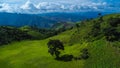 Scenic of idyllic rolling hills landscape with blooming meadows and mountain ranges in the background on a beautiful sunny day