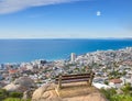 Scenic landscape banner view of a public bench on a cliff or hill overlooking the city and the ocean. Empty, peaceful Royalty Free Stock Photo