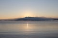 A scenic landscape - fog at dawn in the Chivyrkuisky Bay. The first rays of the rising sun over the mountains Royalty Free Stock Photo
