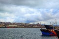 Scenic landscape of harbor with moored fishing boats and ships in Istanbul. Cityscape in the background. Dramatic winter sky. Royalty Free Stock Photo