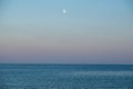 Scenic landscape of the ocean against a sunset sky with the moon in the background Royalty Free Stock Photo