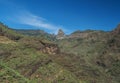 Scenic landscape with Roque de Agando rock at hiking trail through Barranco de Guarimiar Gorge. Green mountain canyon