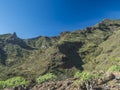 Scenic landscape with Roque de Imada rock and village at hiking trail Barranco de Guarimiar Gorge. Green mountain canyon