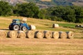 Scenic landscape with tractors that collect bale of straw in the