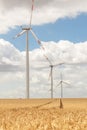 Scenic landscape view of wheat field harvest and big modern wind turbine mill farm against beautiful clouds blue sky Royalty Free Stock Photo