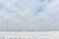 Scenic landscape view of white snowy frosty field and big modern wind turbine mill farm against beautiful blue clouds Royalty Free Stock Photo